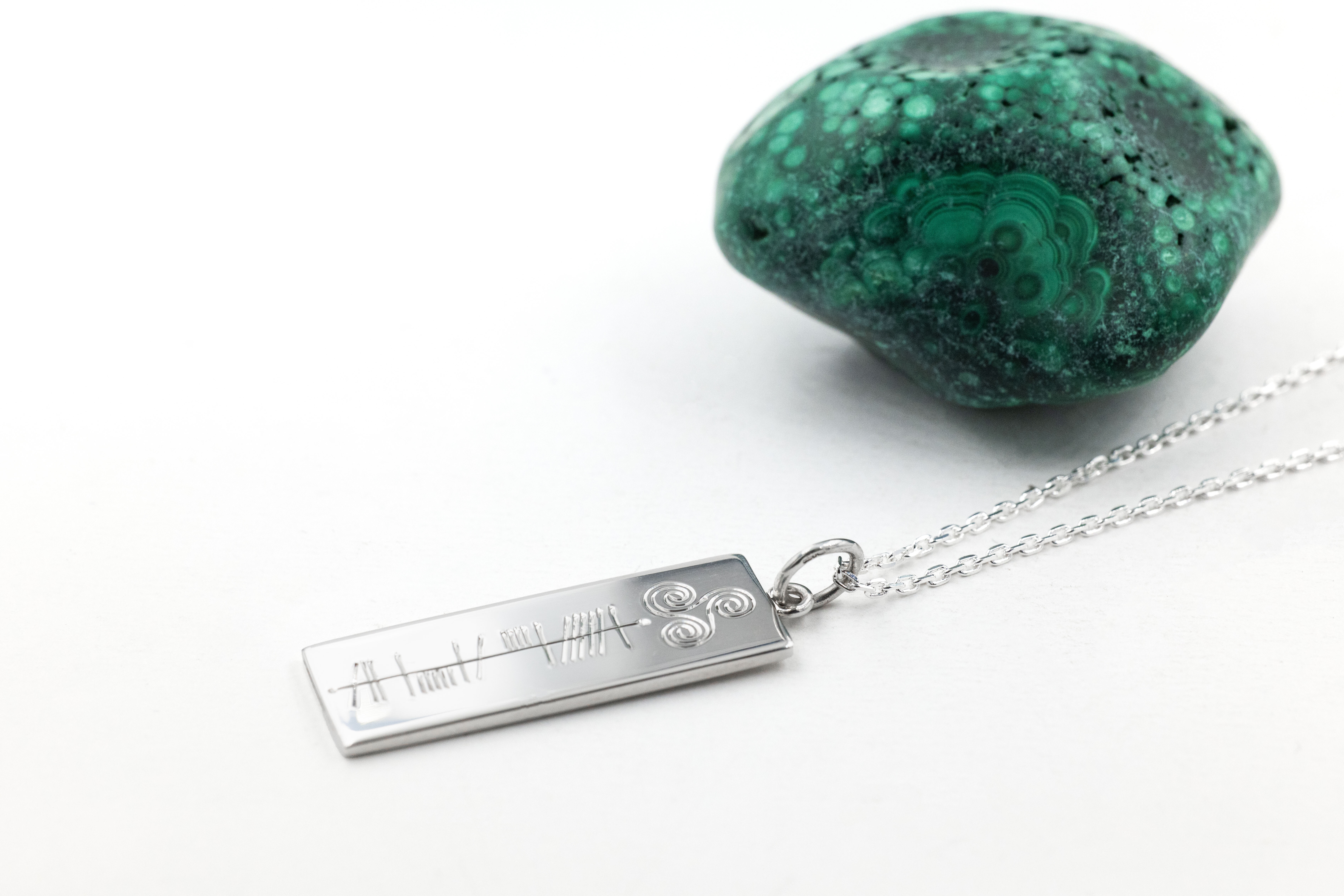 Engravable Sterling Silver Personalizable Ogham & Triskele Necklace With a Polished Finish. Pictured Flat.