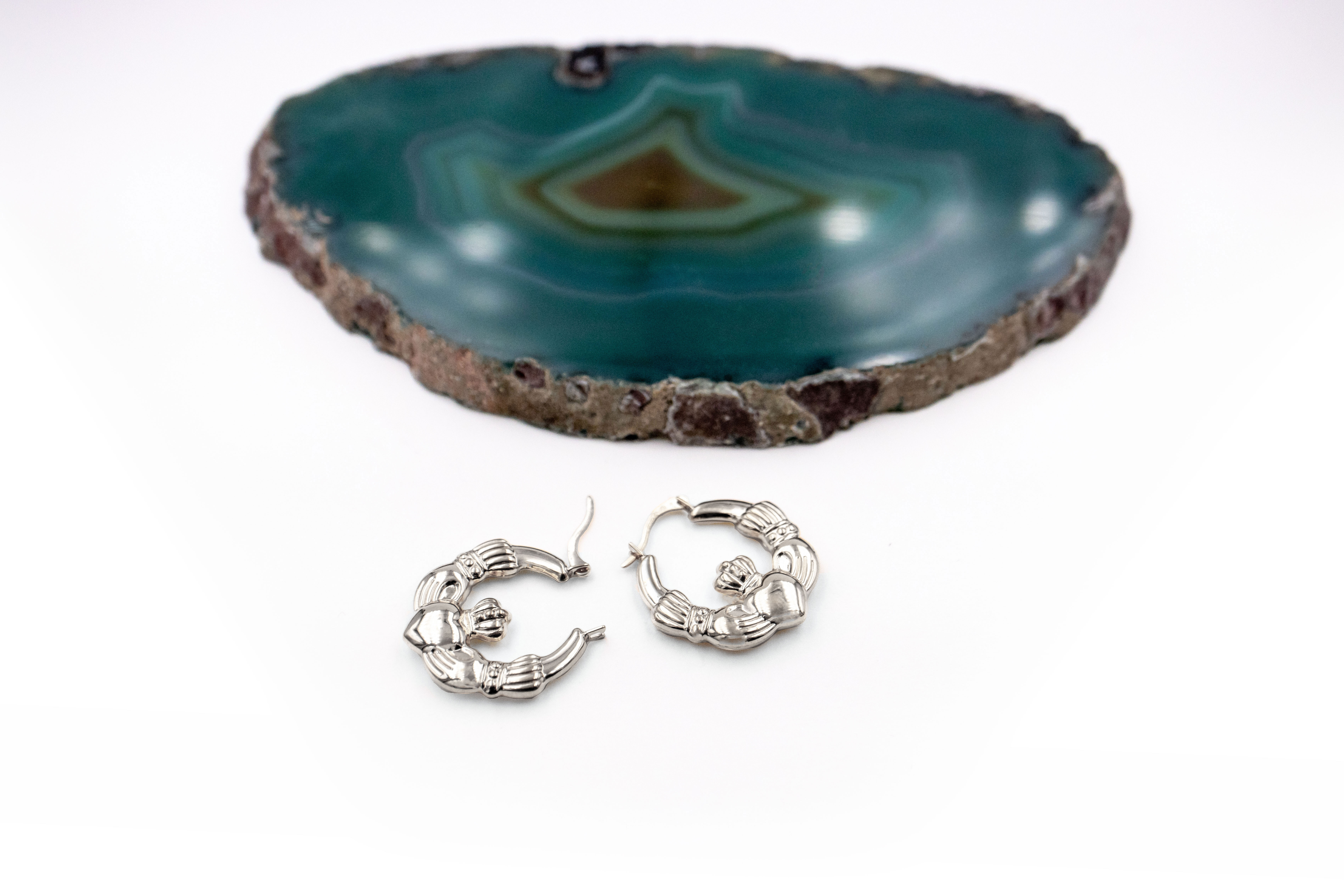 Medium Sized Genuine Sterling Silver Claddagh Earrings With a Polished Finish For Women. Pictured Flat.