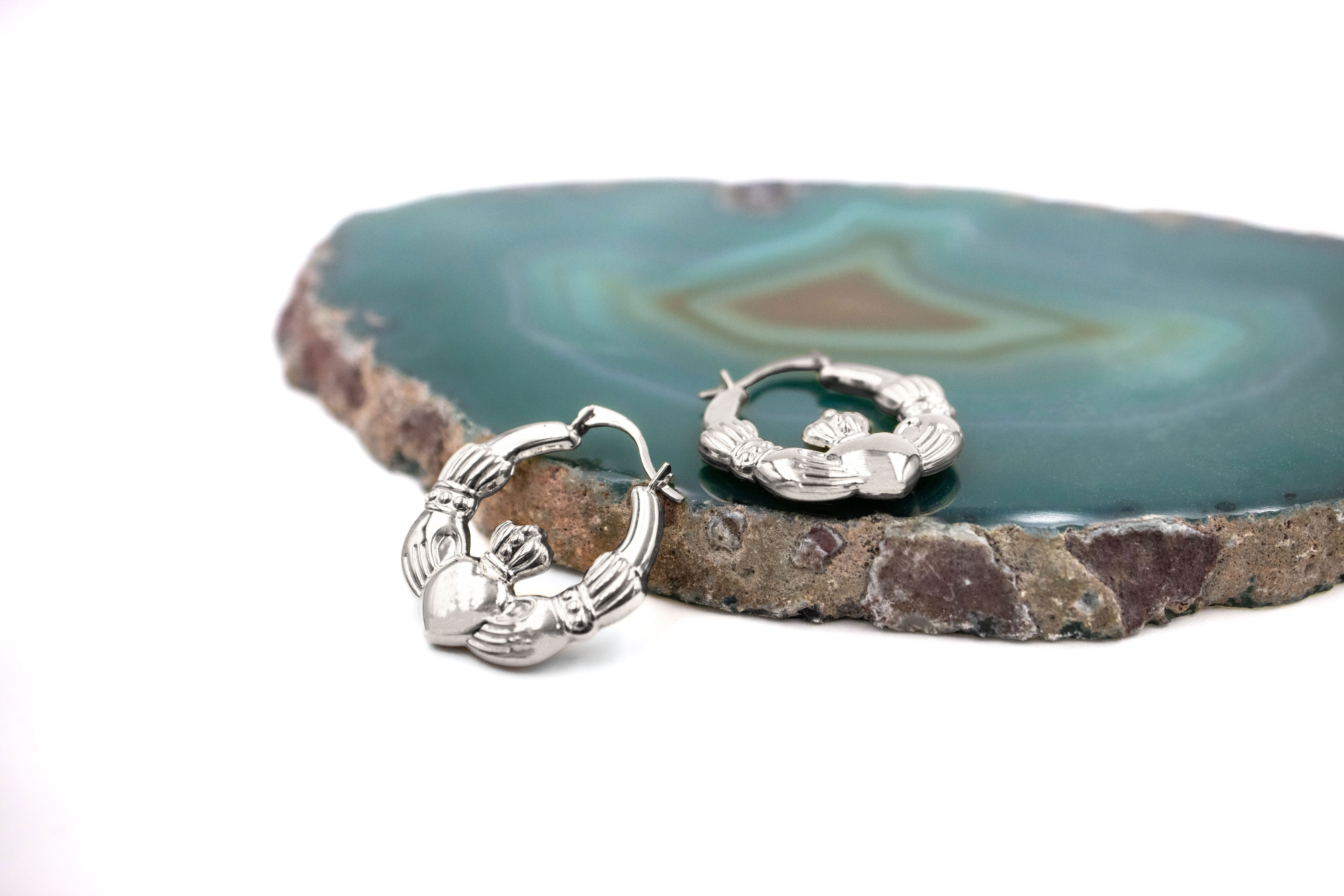 Medium Sized Striking Sterling Silver Claddagh Earrings For Women With a Polished Finish. Pictured Flat.