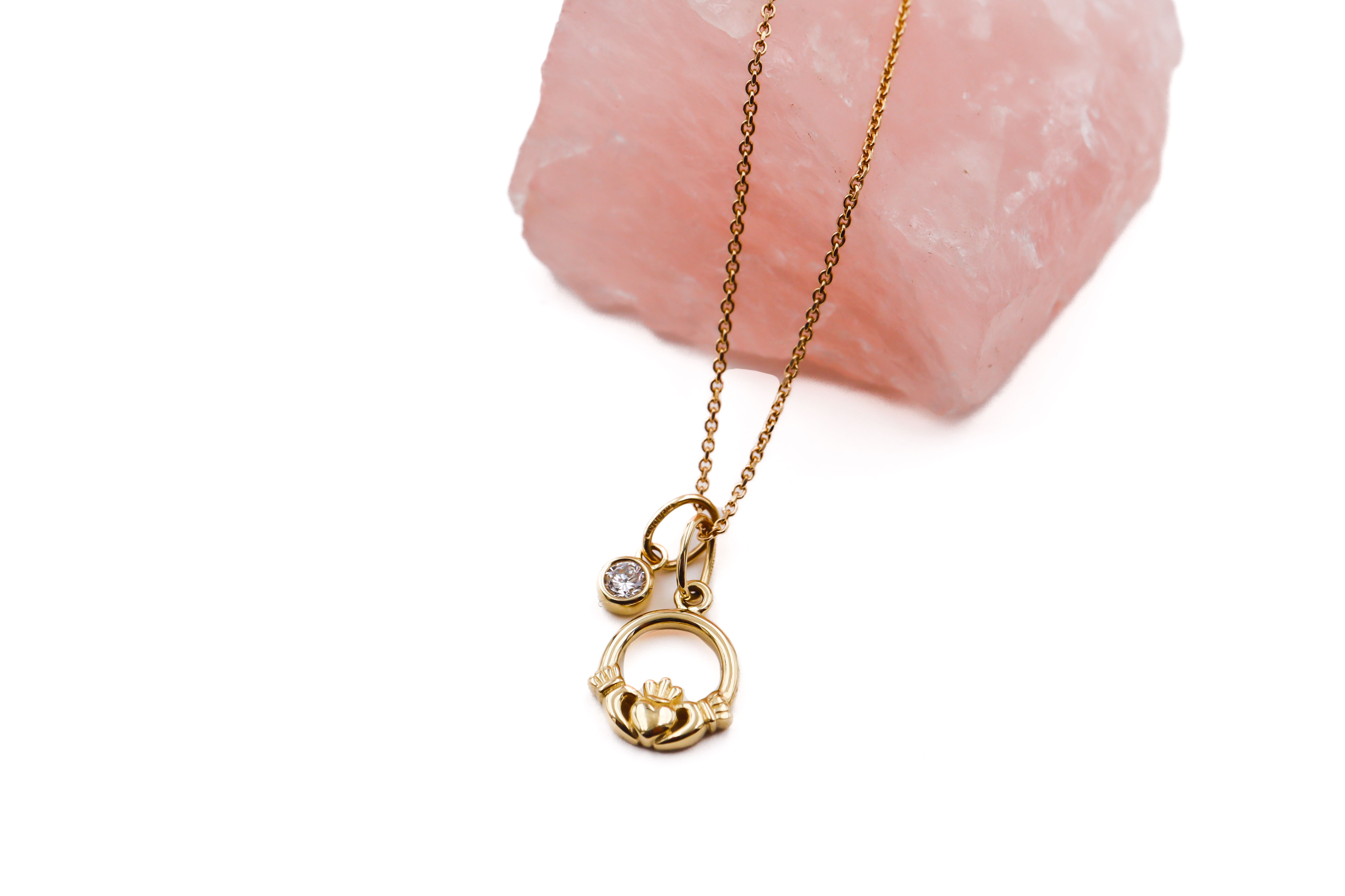 Petite Womens Authentic Polished Yellow Gold Claddagh Necklace. Pictured Flat.